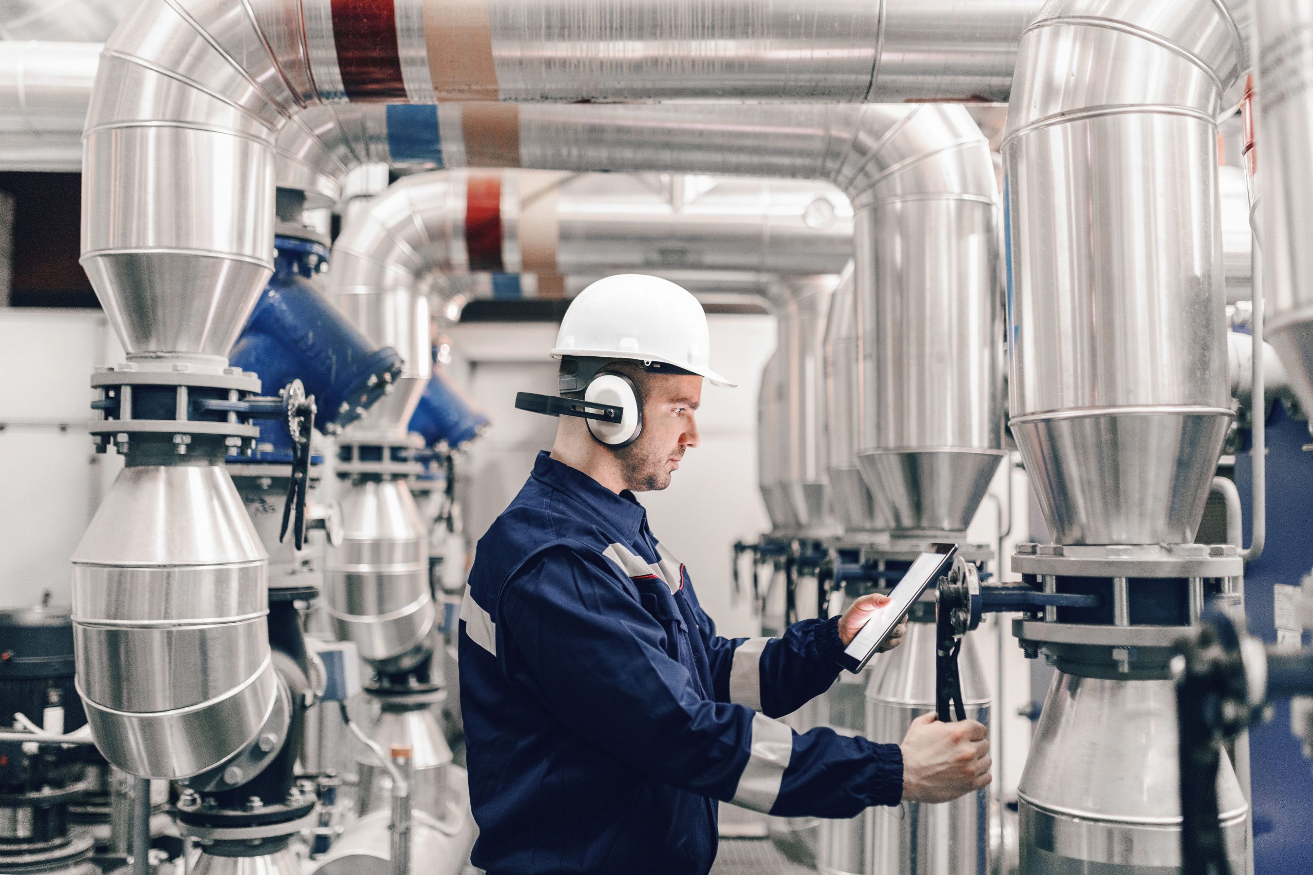 Engineer in safety gear using a tablet to monitor the performance of MET's CDS-FGD technology with Multi-Stage Humidification in an industrial facility.