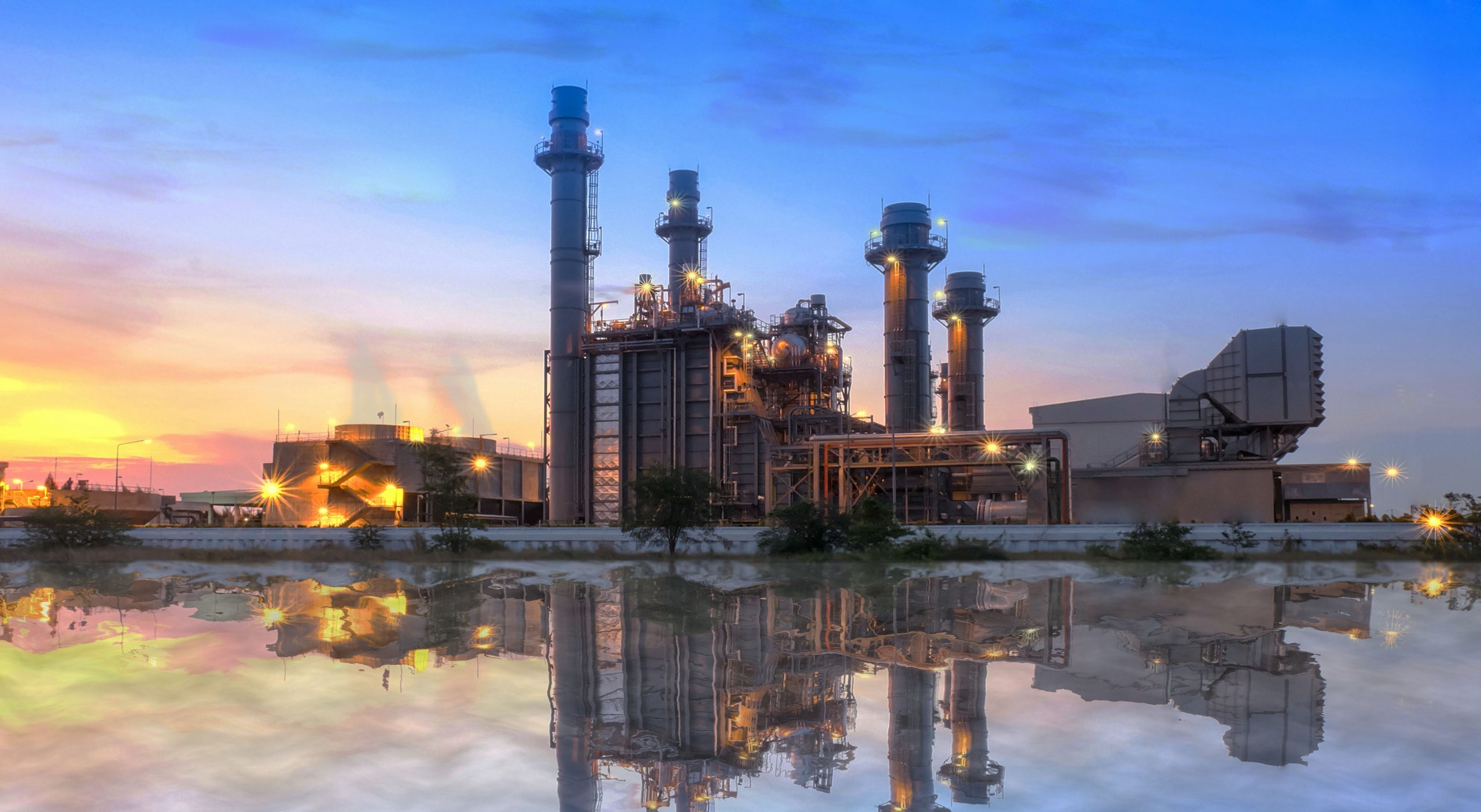 Sunset view of a power plant station with reflection on water, highlighting clean energy production and advanced technology.